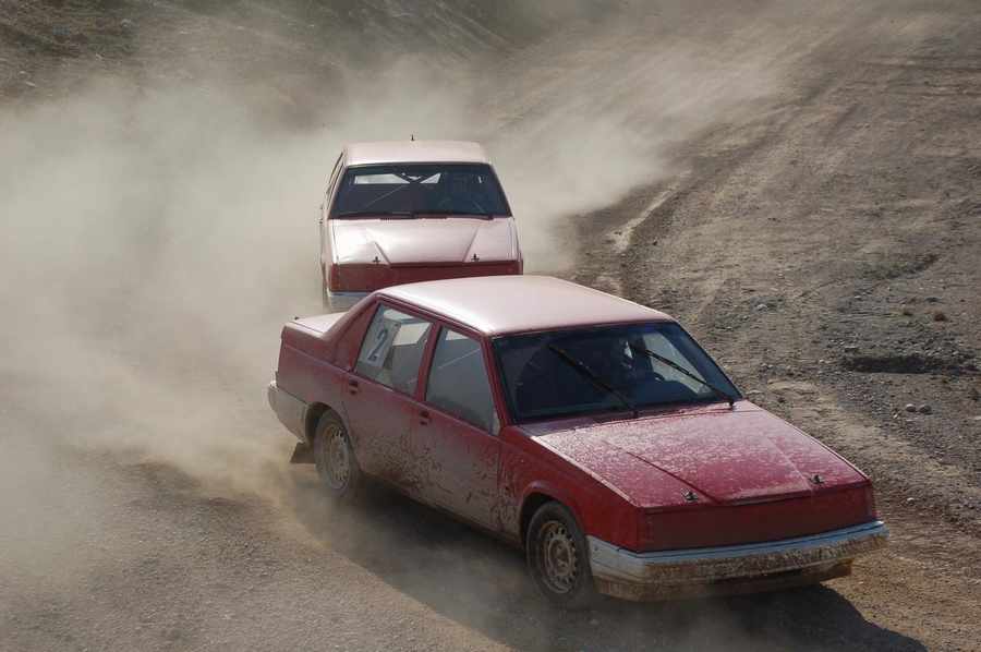 Två röda folkrace-bilar efter varandra.