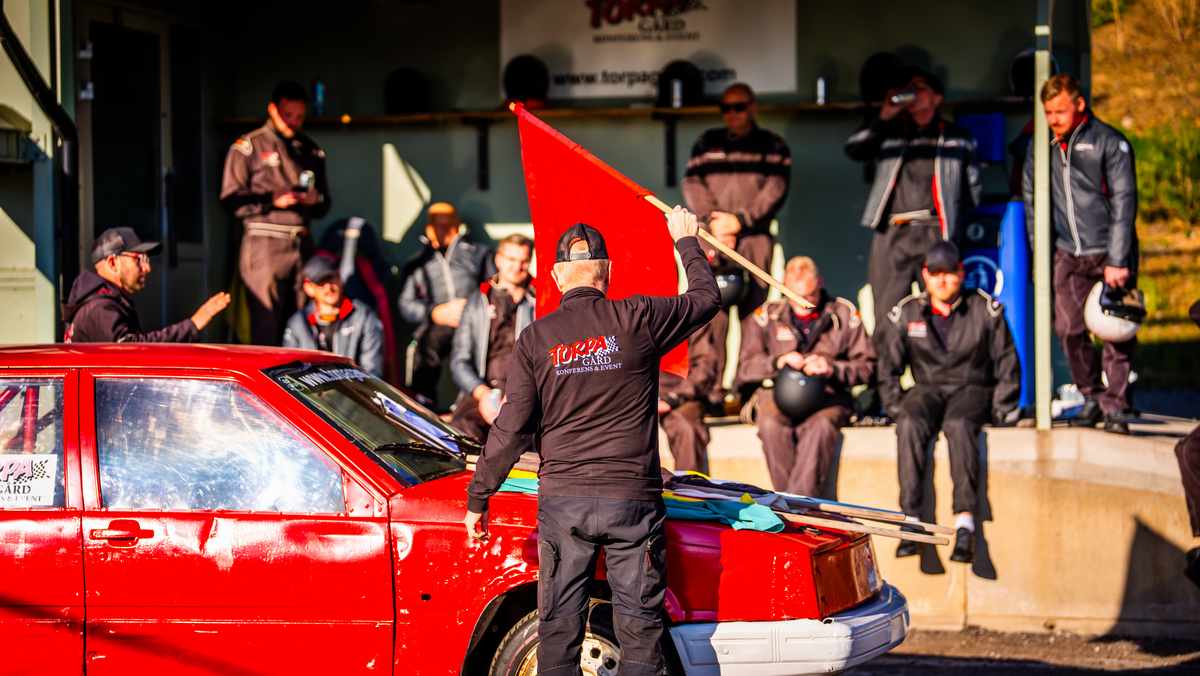 Tre röda, smutsiga folkrace-bilar ligger nästan jämsides på en grus-motorbana.